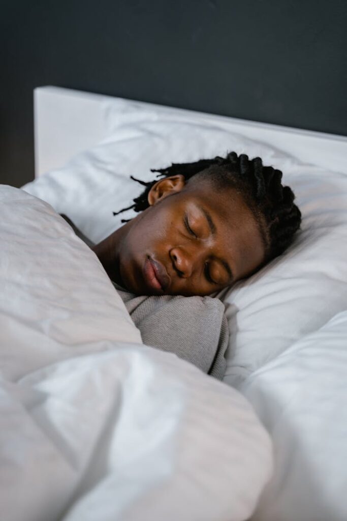 Young man sleeping peacefully in a cozy bed, capturing a calm and restful moment.